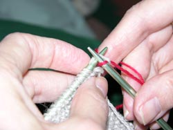 Draw the yarn on the right hand needle through the stitch on the left hand knitting needle